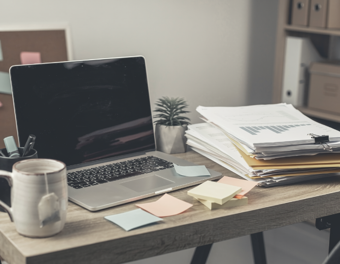 Busy small-business desk with a laptop, paperwork, and sticky notes