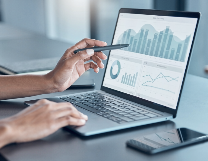 Hands reviewing a chart-filled business dashboard on a laptop